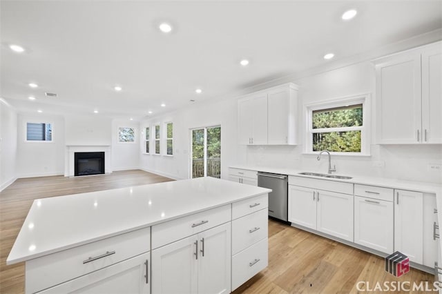 kitchen with sink, white cabinetry, dishwasher, a kitchen island, and a wealth of natural light