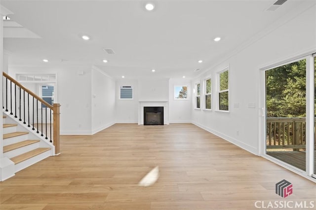 unfurnished living room with crown molding, light hardwood / wood-style floors, and a wealth of natural light