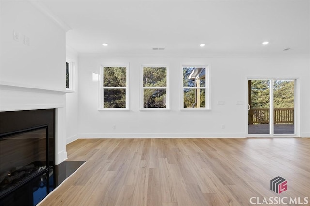 unfurnished living room with ornamental molding and light wood-type flooring