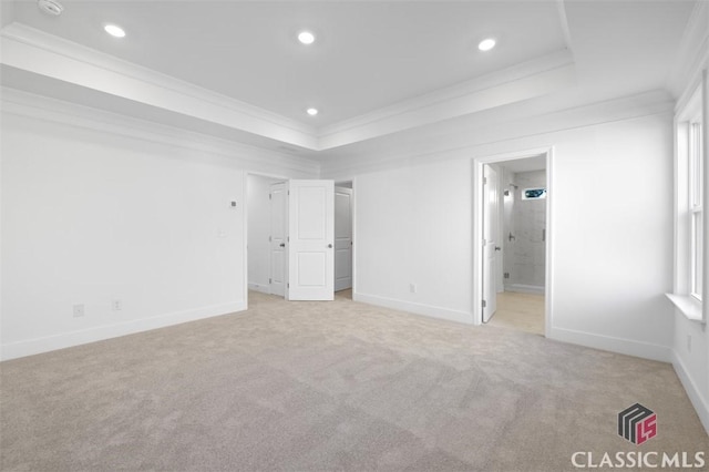 unfurnished bedroom featuring a raised ceiling, crown molding, connected bathroom, and light colored carpet