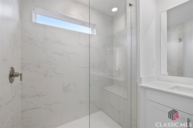 bathroom with a tile shower and vanity