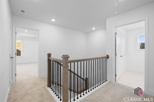 hallway with light colored carpet and a healthy amount of sunlight