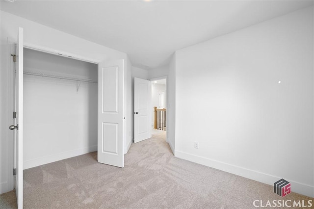 unfurnished bedroom featuring light colored carpet and a closet