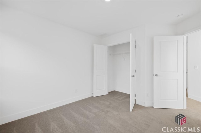 unfurnished bedroom with a closet and light carpet