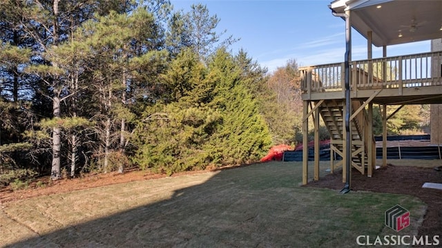 view of yard with ceiling fan and a deck