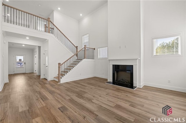 unfurnished living room with a towering ceiling, plenty of natural light, and light hardwood / wood-style floors