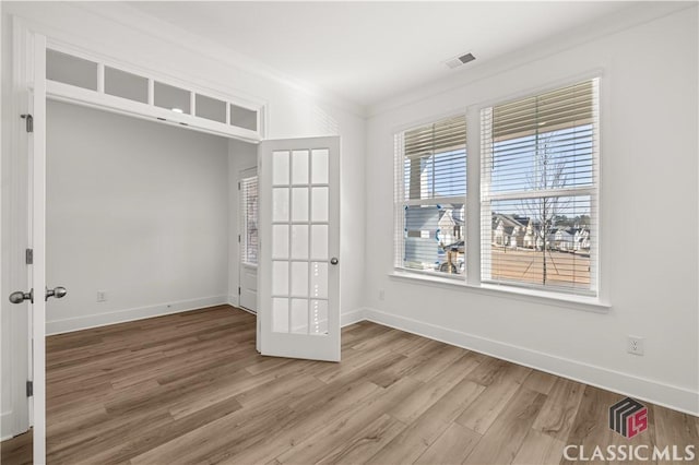 unfurnished bedroom featuring wood-type flooring, crown molding, and french doors