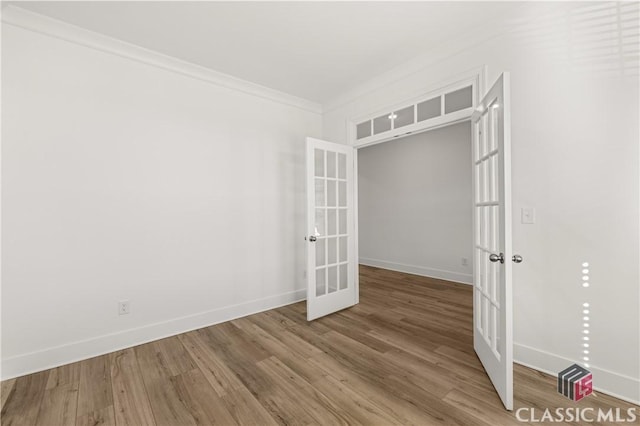 spare room featuring french doors, crown molding, and hardwood / wood-style flooring