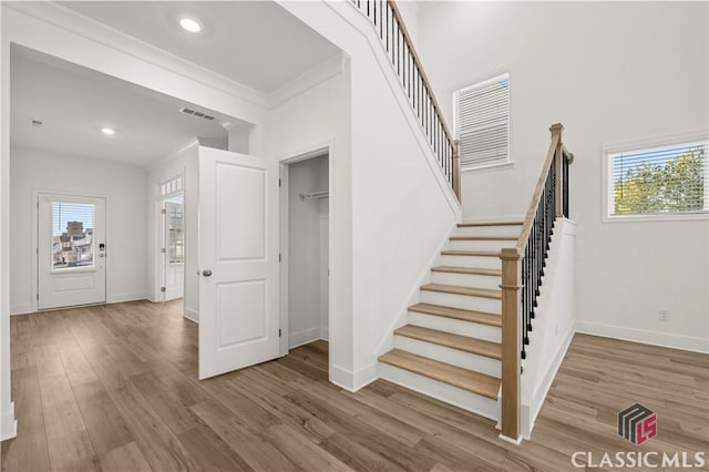 staircase featuring wood-type flooring and ornamental molding