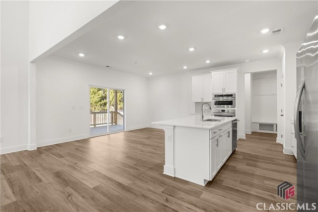 kitchen with sink, white cabinetry, a center island with sink, stainless steel appliances, and hardwood / wood-style floors