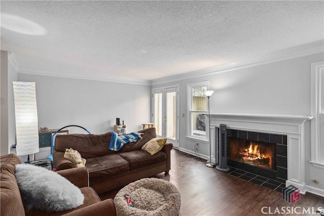 living room featuring a tile fireplace, dark hardwood / wood-style floors, a textured ceiling, and ornamental molding