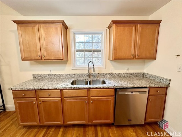 kitchen with dishwasher, light stone countertops, sink, and light hardwood / wood-style floors