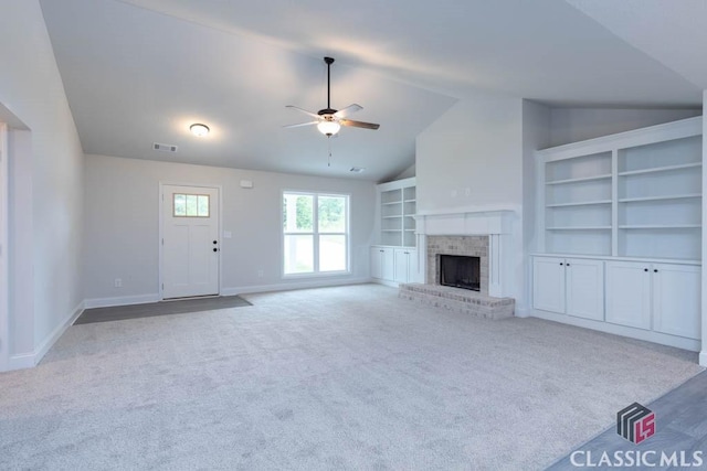 unfurnished living room featuring light carpet, a brick fireplace, built in shelves, and ceiling fan