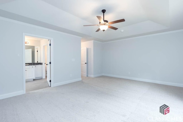 unfurnished bedroom with connected bathroom, ornamental molding, light colored carpet, and a raised ceiling