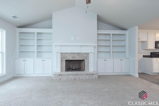 unfurnished living room featuring a brick fireplace, light carpet, and lofted ceiling