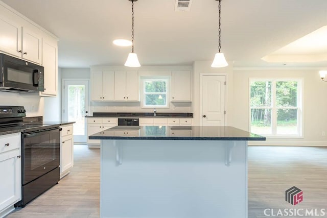 kitchen featuring white cabinetry, a kitchen island, hanging light fixtures, and black appliances