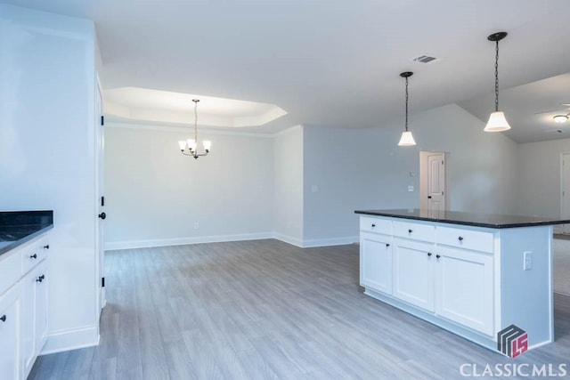 kitchen featuring hanging light fixtures, a center island, a tray ceiling, light hardwood / wood-style floors, and white cabinets