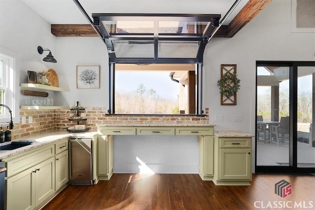 kitchen with sink, light stone counters, green cabinetry, dark hardwood / wood-style flooring, and a wealth of natural light