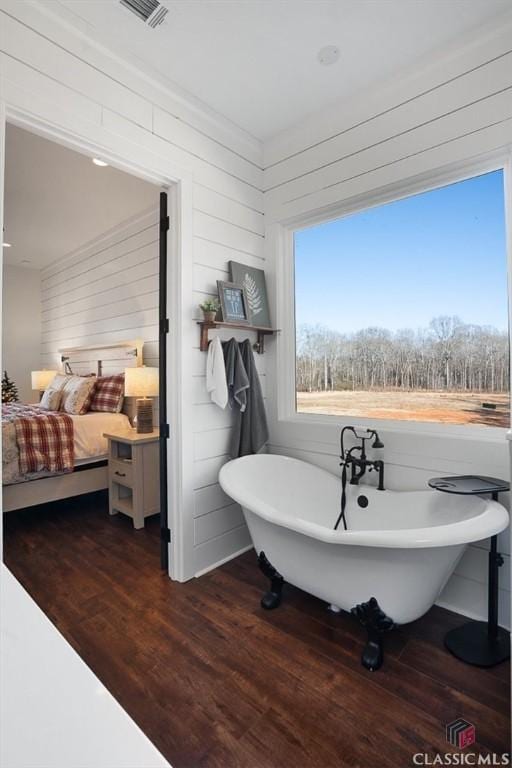 bathroom featuring wood-type flooring, wooden walls, and a washtub