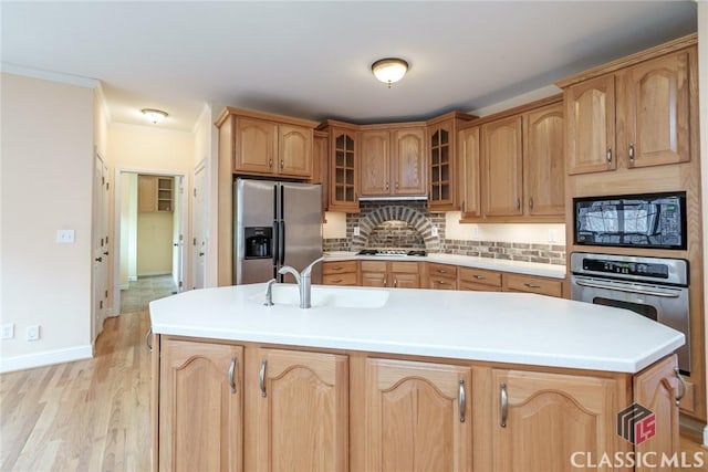 kitchen featuring sink, light hardwood / wood-style flooring, a kitchen island with sink, stainless steel appliances, and tasteful backsplash