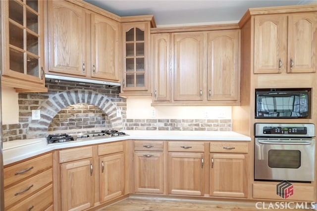 kitchen with light brown cabinetry, decorative backsplash, and appliances with stainless steel finishes