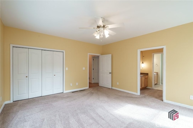 unfurnished bedroom with light carpet, ensuite bath, a closet, and ceiling fan