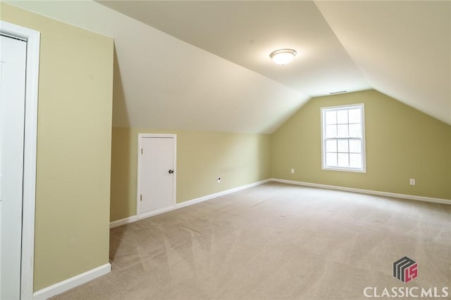 bonus room with vaulted ceiling and light carpet