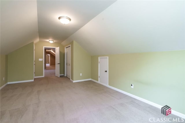 additional living space featuring light colored carpet and vaulted ceiling