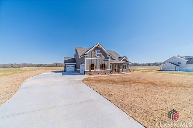 craftsman-style house featuring board and batten siding, covered porch, a front lawn, and concrete driveway