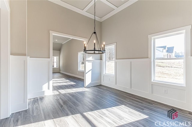 unfurnished dining area featuring dark wood-type flooring, a wealth of natural light, ornamental molding, and a chandelier