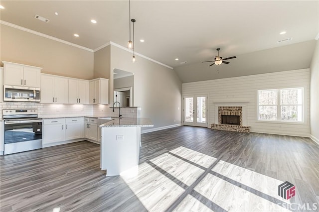 kitchen with appliances with stainless steel finishes, decorative light fixtures, white cabinetry, light stone counters, and kitchen peninsula