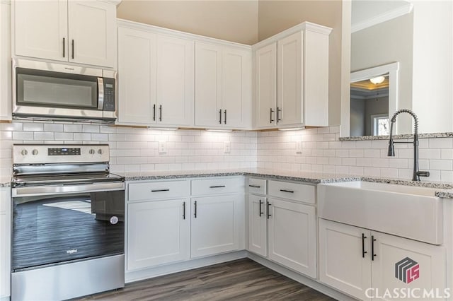 kitchen with appliances with stainless steel finishes, sink, white cabinets, and light stone counters