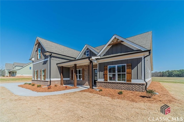 view of front of property with a shingled roof, board and batten siding, and brick siding