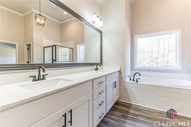 bathroom with independent shower and bath, ornamental molding, hardwood / wood-style floors, and vanity