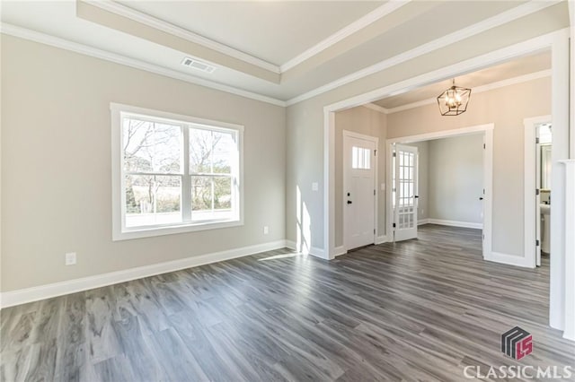 entrance foyer with dark wood-type flooring, ornamental molding, a tray ceiling, and an inviting chandelier