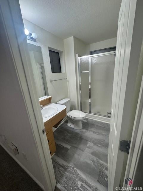 bathroom with a textured ceiling, toilet, vanity, and a shower with door