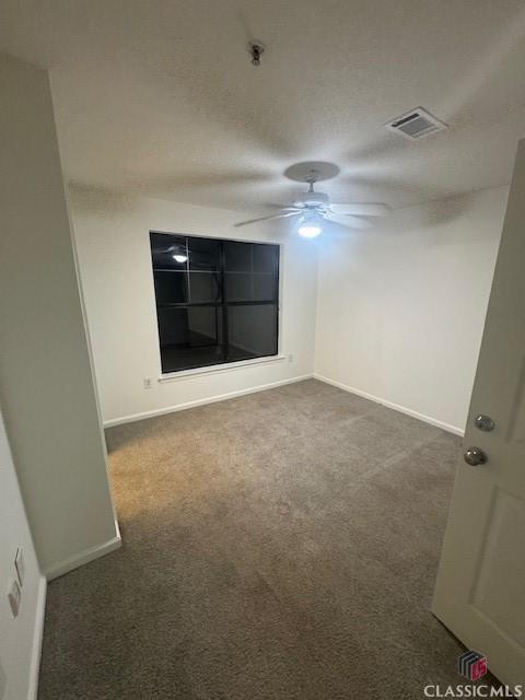 carpeted empty room with ceiling fan and a textured ceiling