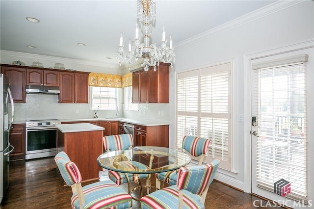 kitchen with appliances with stainless steel finishes, backsplash, ornamental molding, a kitchen island, and dark hardwood / wood-style flooring