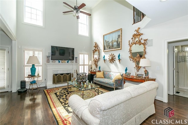 living room with a tiled fireplace, dark hardwood / wood-style floors, and ceiling fan