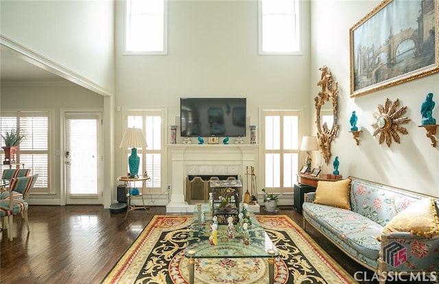 living room with dark hardwood / wood-style flooring, a wealth of natural light, and ornamental molding