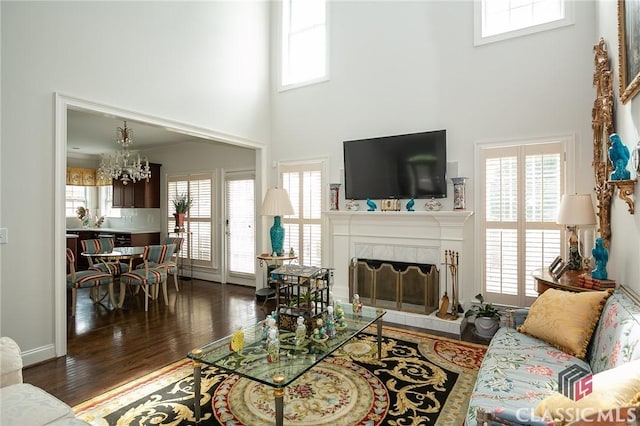 living room featuring a healthy amount of sunlight, dark hardwood / wood-style floors, a tile fireplace, and a high ceiling