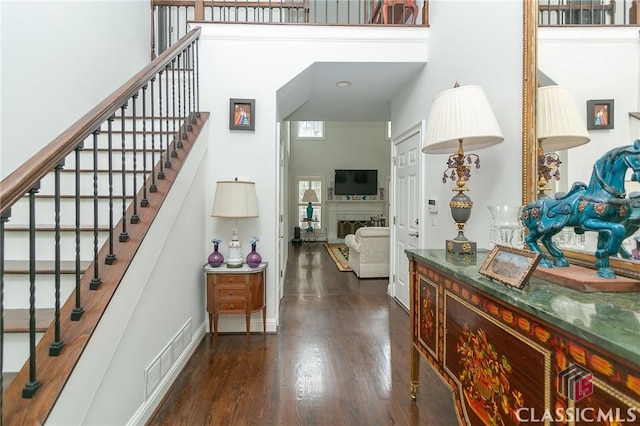 foyer entrance with a towering ceiling and dark wood-type flooring