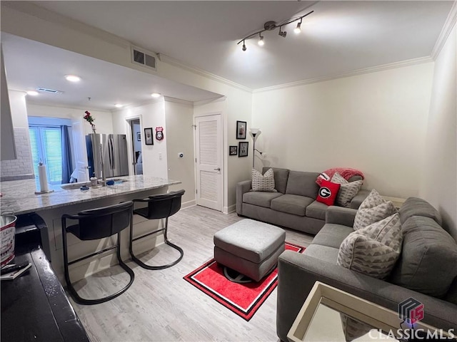 living room featuring crown molding, rail lighting, and light wood-type flooring