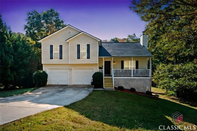 split level home featuring a garage, covered porch, and a lawn