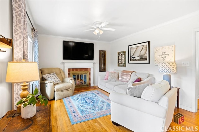 living room with ceiling fan, ornamental molding, a fireplace, and hardwood / wood-style floors