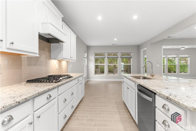 kitchen with white cabinetry, appliances with stainless steel finishes, light stone countertops, and sink