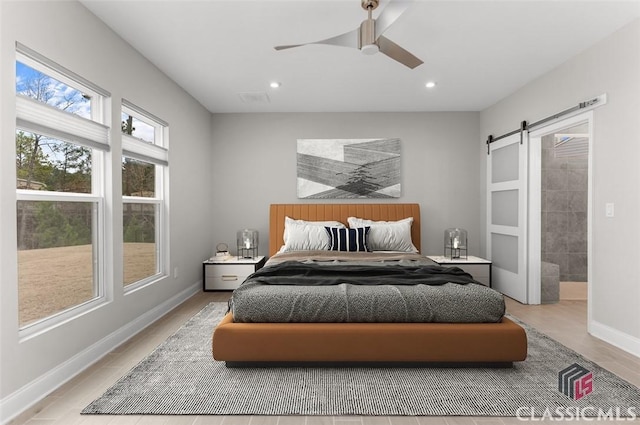 bedroom featuring ceiling fan and a barn door