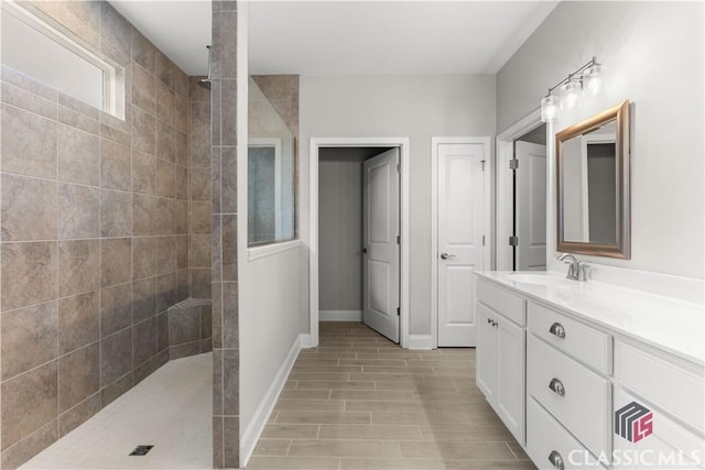 bathroom with tiled shower and vanity