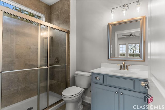 bathroom with vanity, toilet, a shower with door, and a wealth of natural light