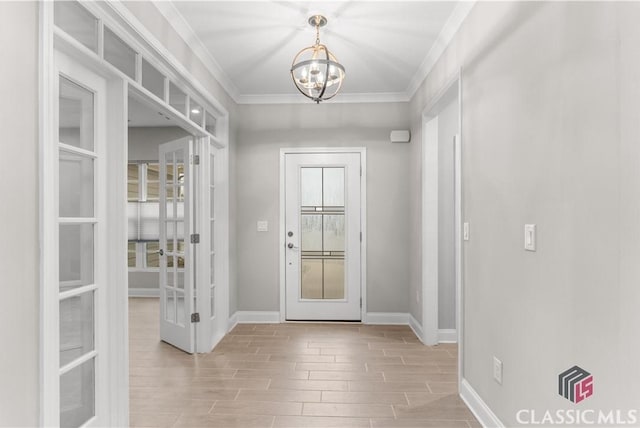 entryway with ornamental molding, an inviting chandelier, and french doors